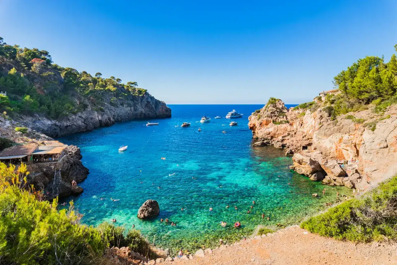 Traumhafte Bucht Cala Pi mit t&uuml;rkisfarbenem Wasser, vielen Booten und Badeg&auml;sten.