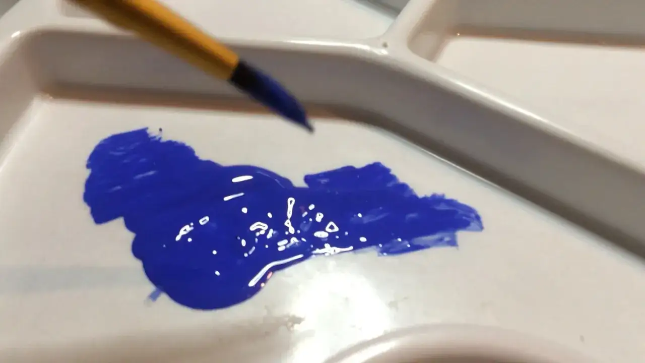 Pinceau sur une palette avec de la peinture bleue trop épaisse. Que faire pour la diluer ?