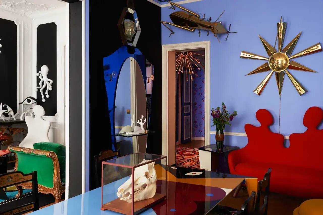 Un sal&oacute;n surrealista con **cuadros de Dal&iacute;** inspirando la decoraci&oacute;n, un sof&aacute; rojo con forma de silueta y un cr&aacute;neo de animal en una vitrina.