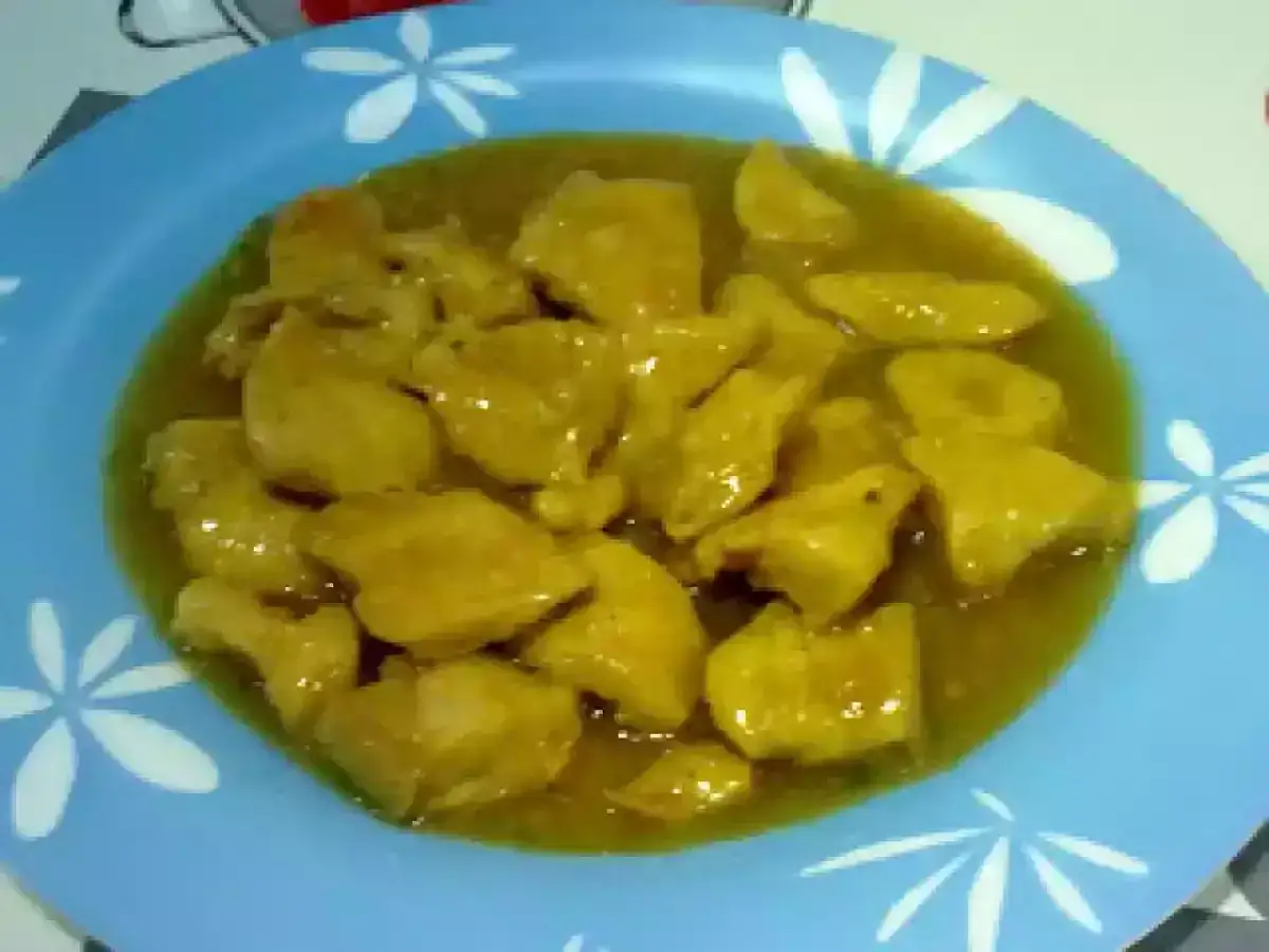 Sabroso pollo en salsa, con un toque de cebolla y cerveza, servido en un plato azul.