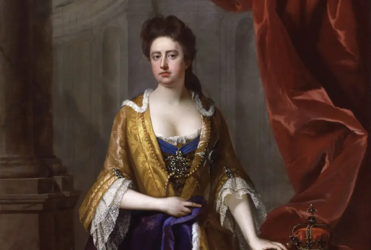 Ritratto di **Regina Anna la favorita**, con sontuosi abiti dorati e gioielli, accanto a una corona e drappi rossi.