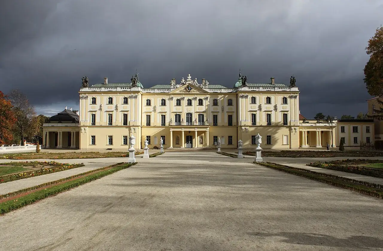 Pałac Branickich w Białymstoku, majestatyczna budowla z ogrodem, pod burzowym niebem.
