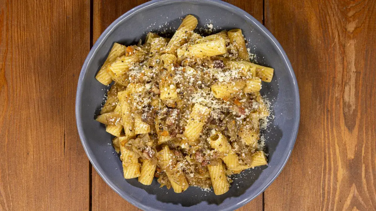 Piatto di pasta con sugo saporito, un tocco di finta genovese napoletana, cosparso di formaggio grattugiato e pepe nero.