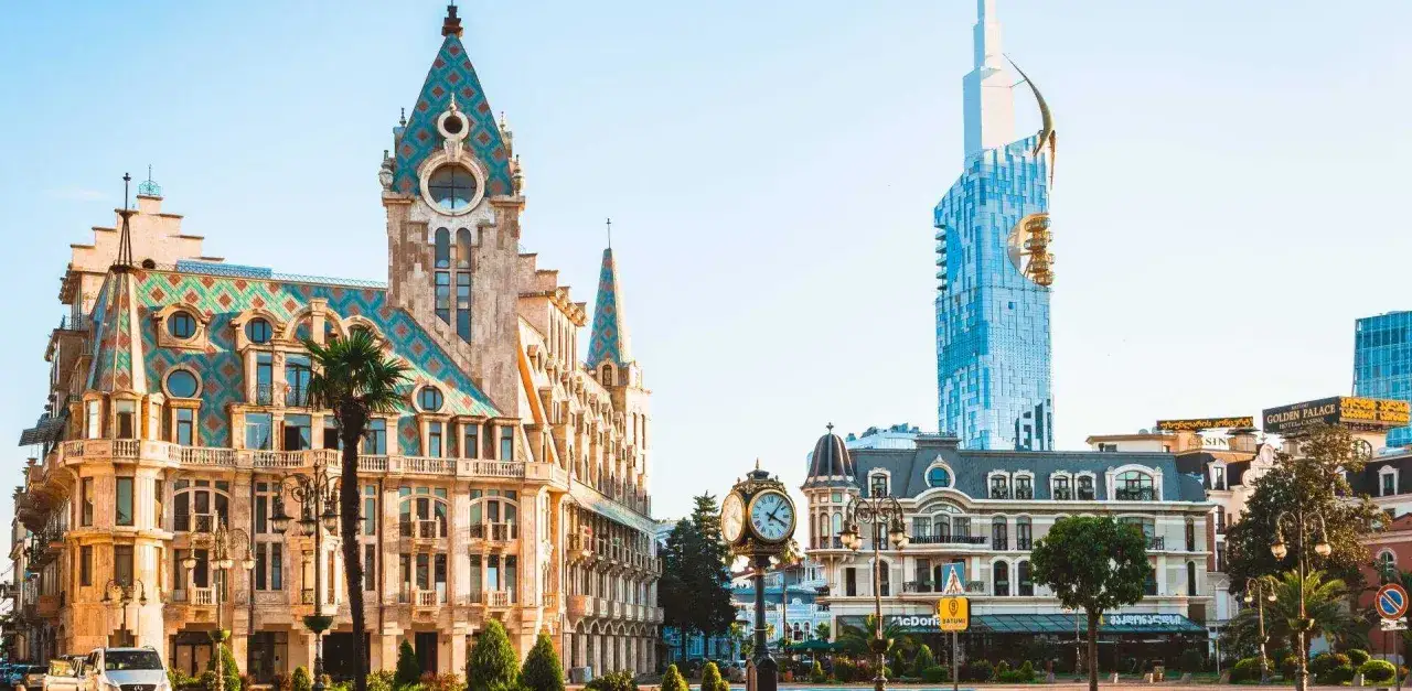 Batumi, stolica Adżarii, z charakterystycznym budynkiem z kolorowym dachem i nowoczesnym wieżowcem w tle.