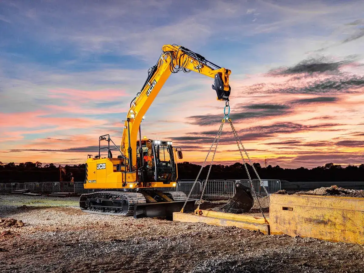 Żółta koparka JCB pracuje na budowie o zachodzie słońca. Zastanawiasz się, kurs na koparkę ile trwa?