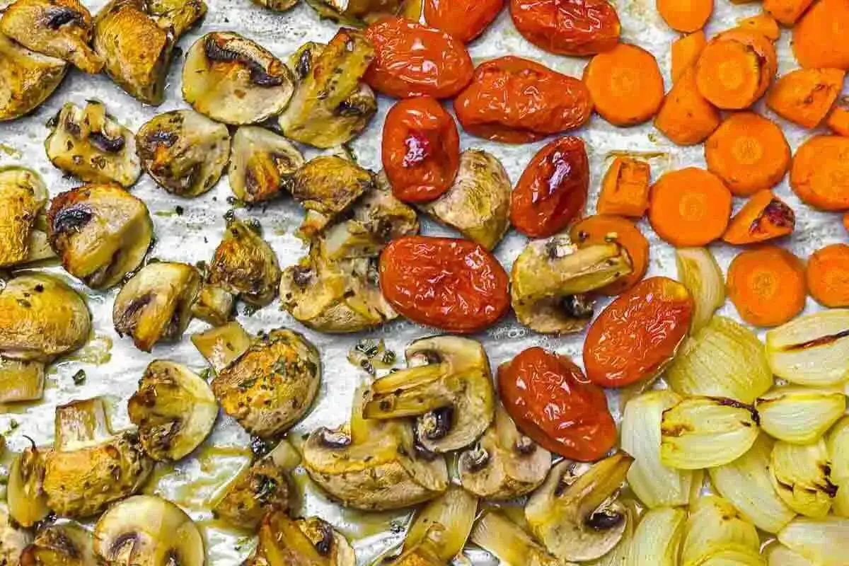 Pieczone warzywa niskowęglowodanowe: pieczarki, pomidorki koktajlowe, marchewka i cebula na blasze.