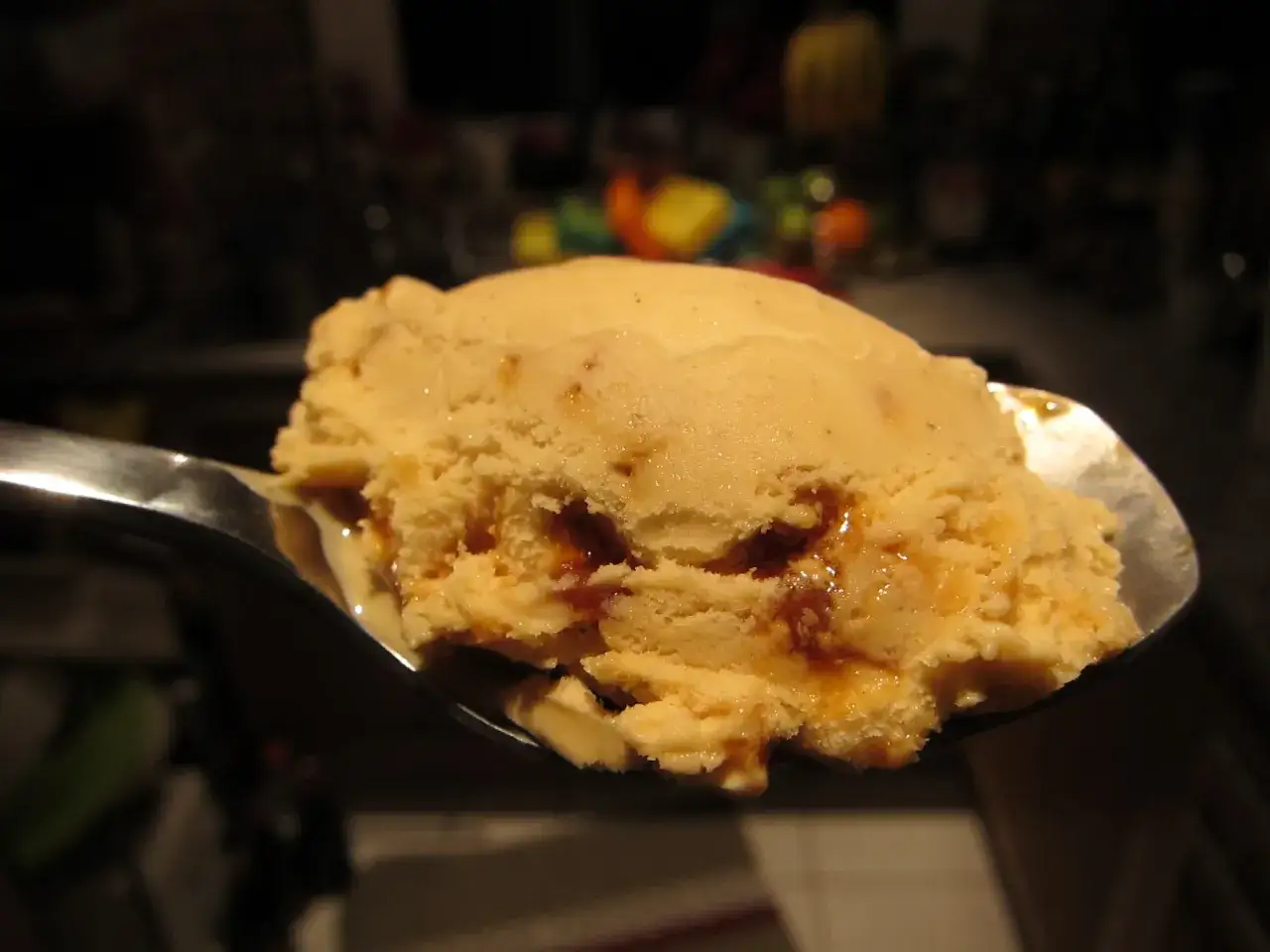 Ein Löffel cremiges Crema Catalana Eis mit karamelligen Wirbeln, bereit zum Genuss.