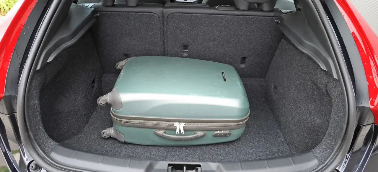 Bagażnik Volvo V40 D3 mieści zieloną walizkę.
