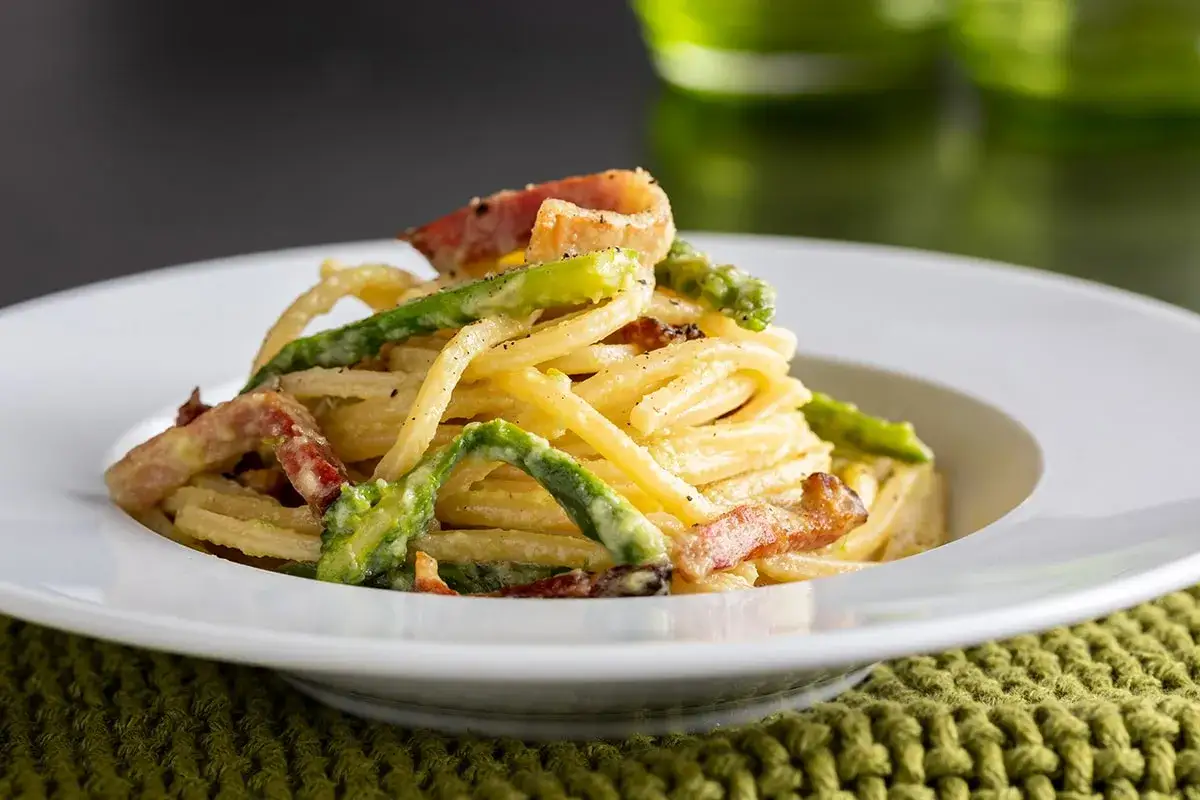 Un piatto invitante di pasta con asparagi e pancetta croccante, condita con una cremosa salsa.