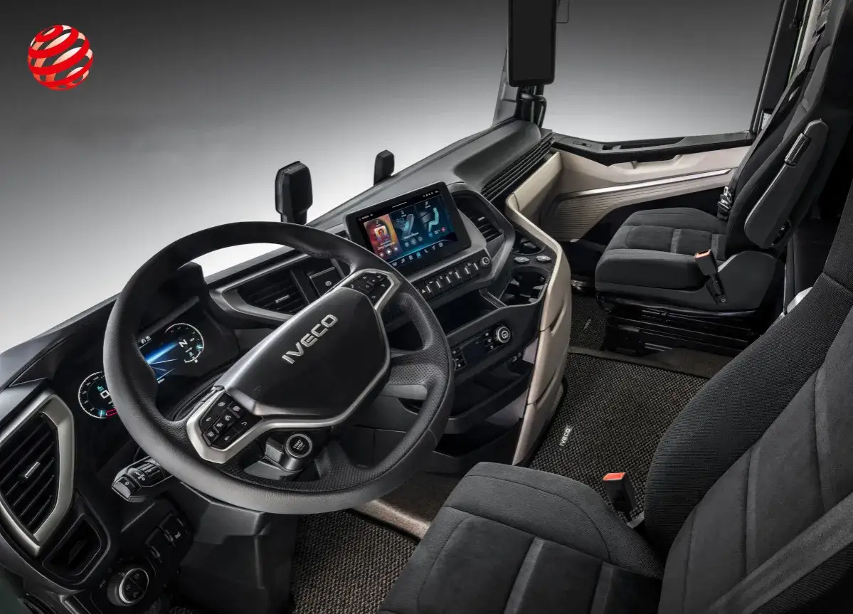Wnętrze Iveco Trakker: kierownica z logo, ekran multimedialny, fotele kierowcy i pasażera.