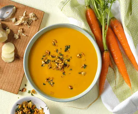 cremige M&ouml;hren Ingwer Suppe in einer Sch&uuml;ssel mit Toppings