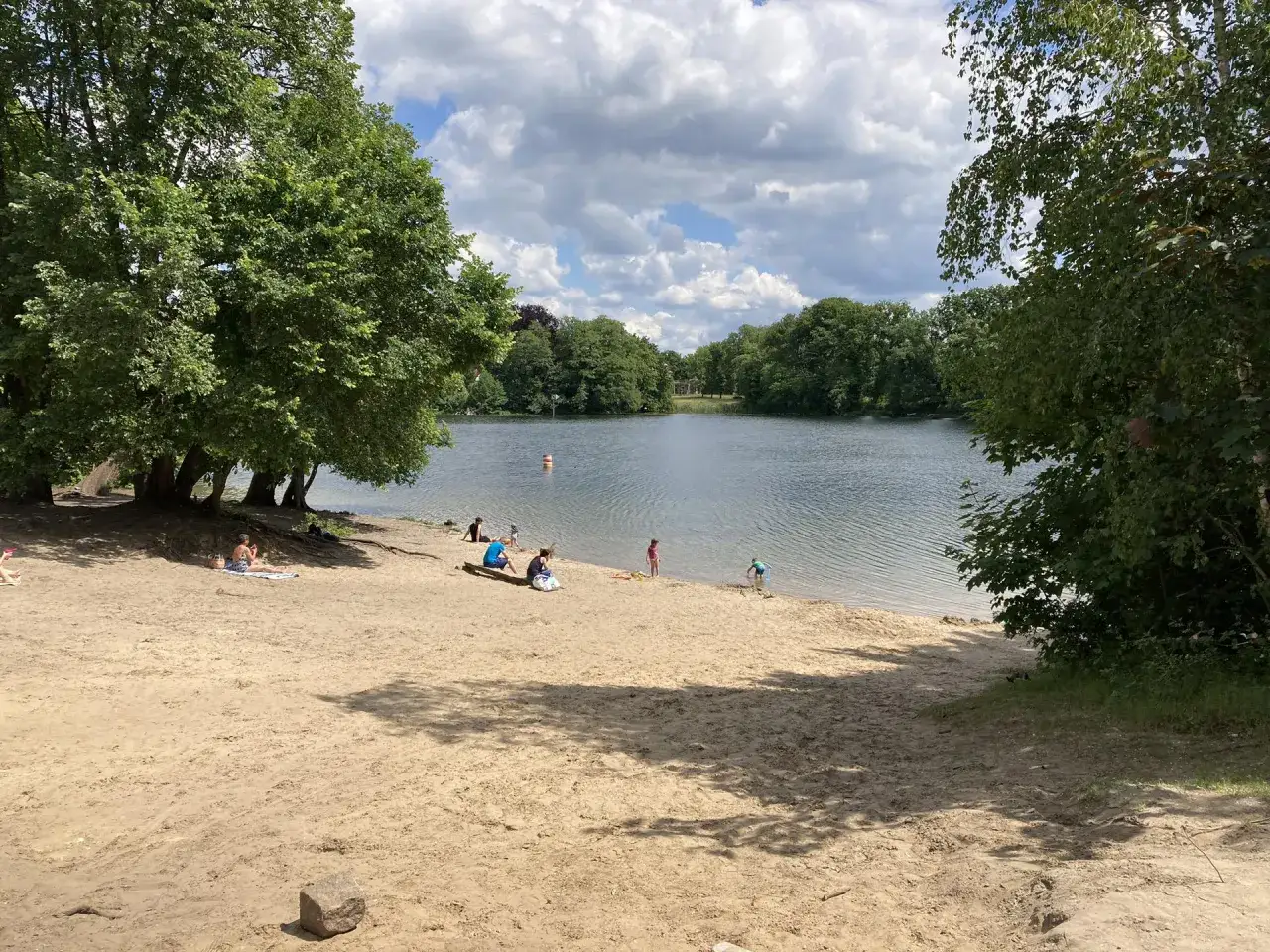 Sonniger Tag am Tegeler See. Menschen entspannen am Sandstrand und genie&szlig;en das k&uuml;hle Nass beim Tegeler See baden.