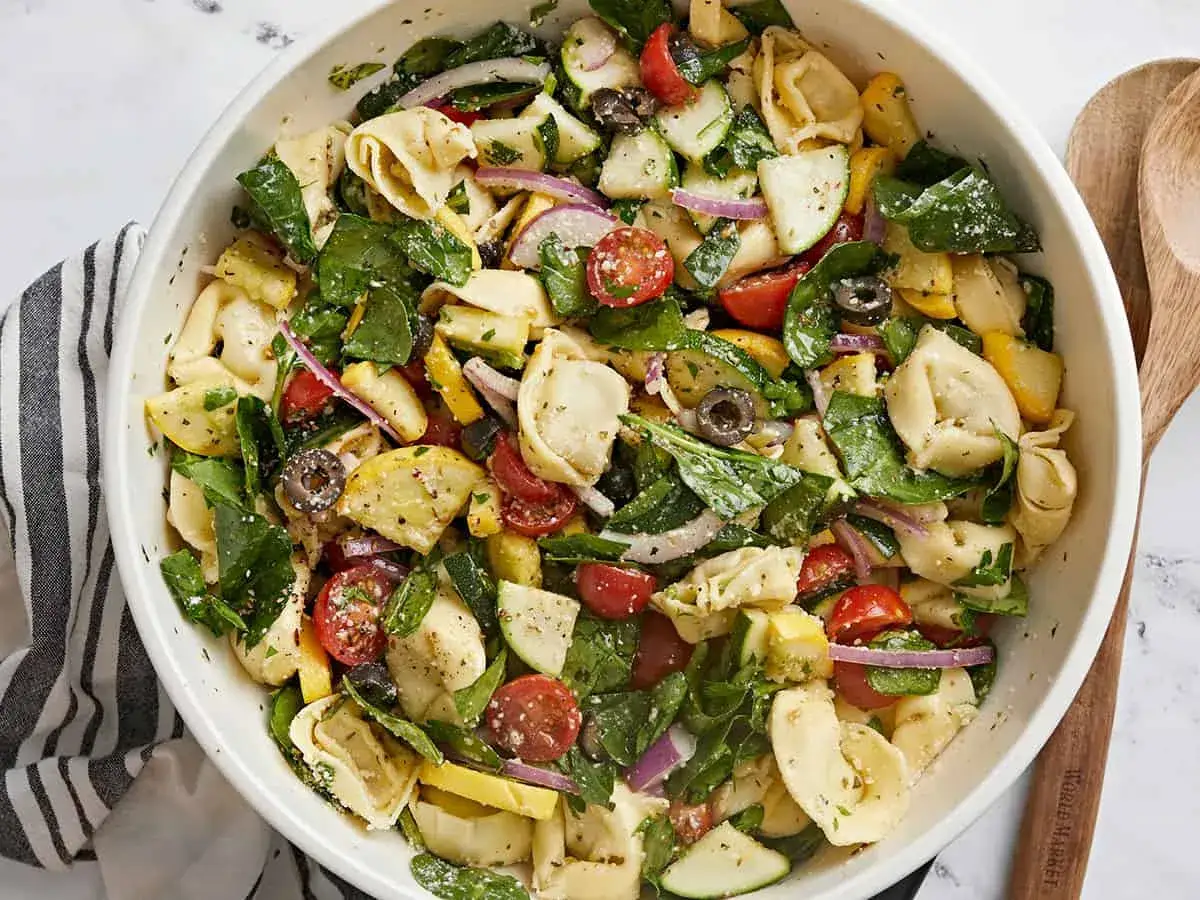 Ein bunter Tortellini Salat mit frischem Gem&uuml;se wie Tomaten, Zucchini, Oliven und roten Zwiebeln, garniert mit Spinat.
