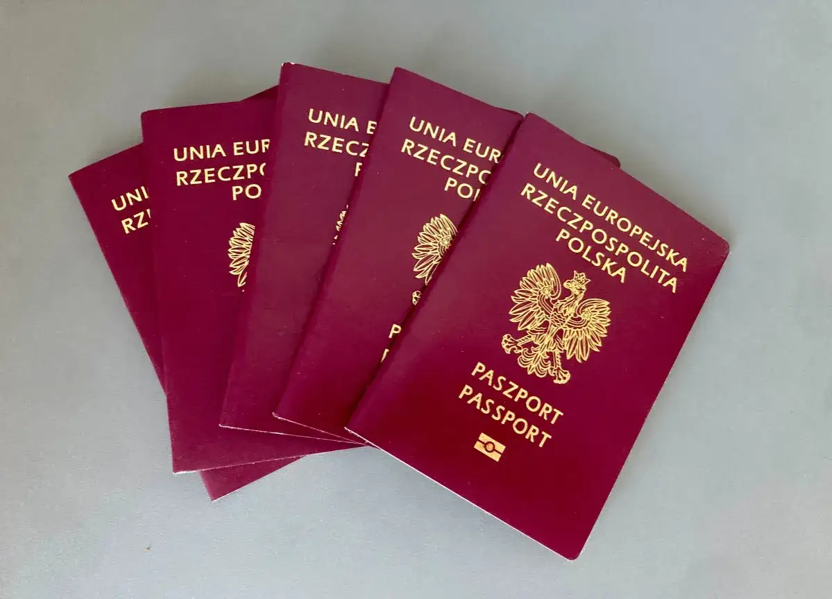 Kilka paszportów Rzeczypospolitej Polskiej ułożonych na szarym tle. Polski paszport ranking jest wysoki.