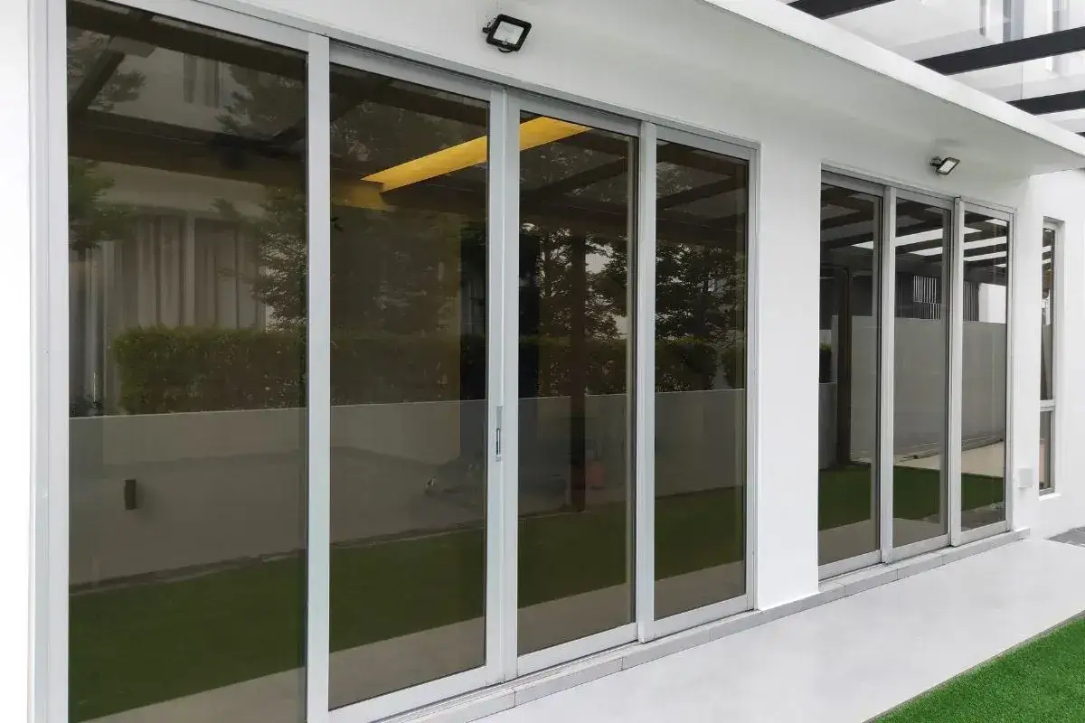 Modern sliding doors with tinted glass offer stylish soluciones para ventanas con mucho sol, reflecting the outdoors and enhancing privacy.