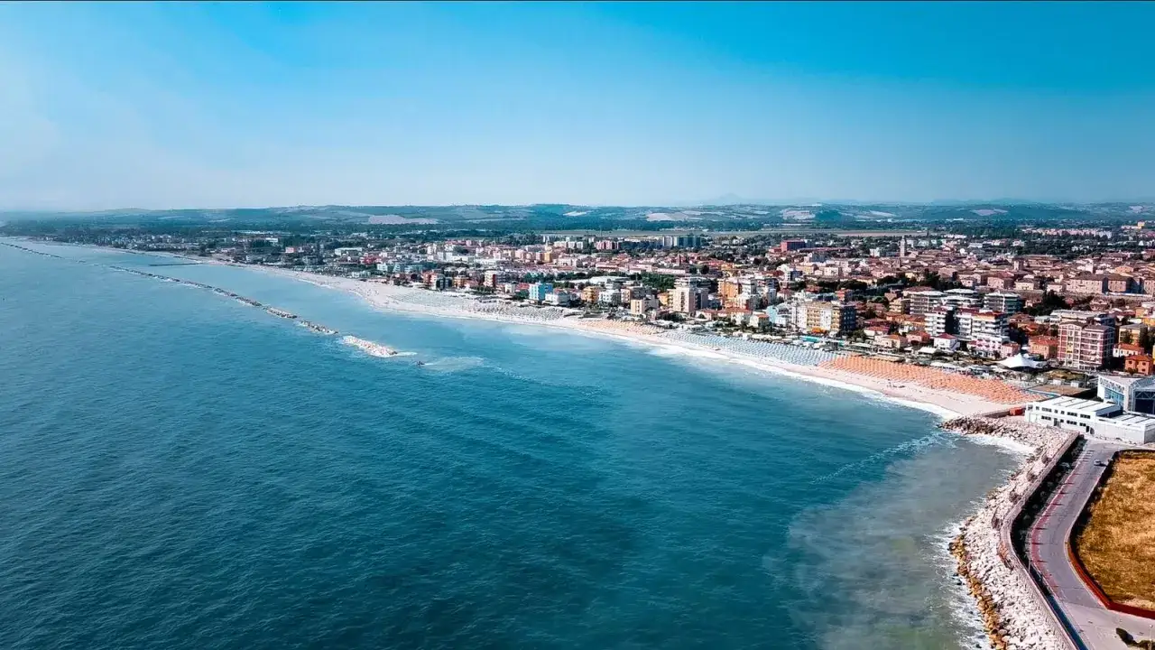 Vista aerea di Fano mare, con la spiaggia dorata, il mare blu e la citt&agrave; che si estende all'orizzonte.