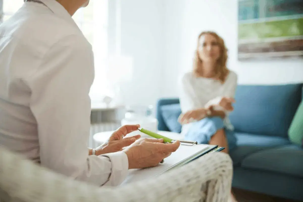 Terapia to pierwszy krok, jak wyjść z depresji. Terapeuta słucha pacjentki, notując ważne informacje.