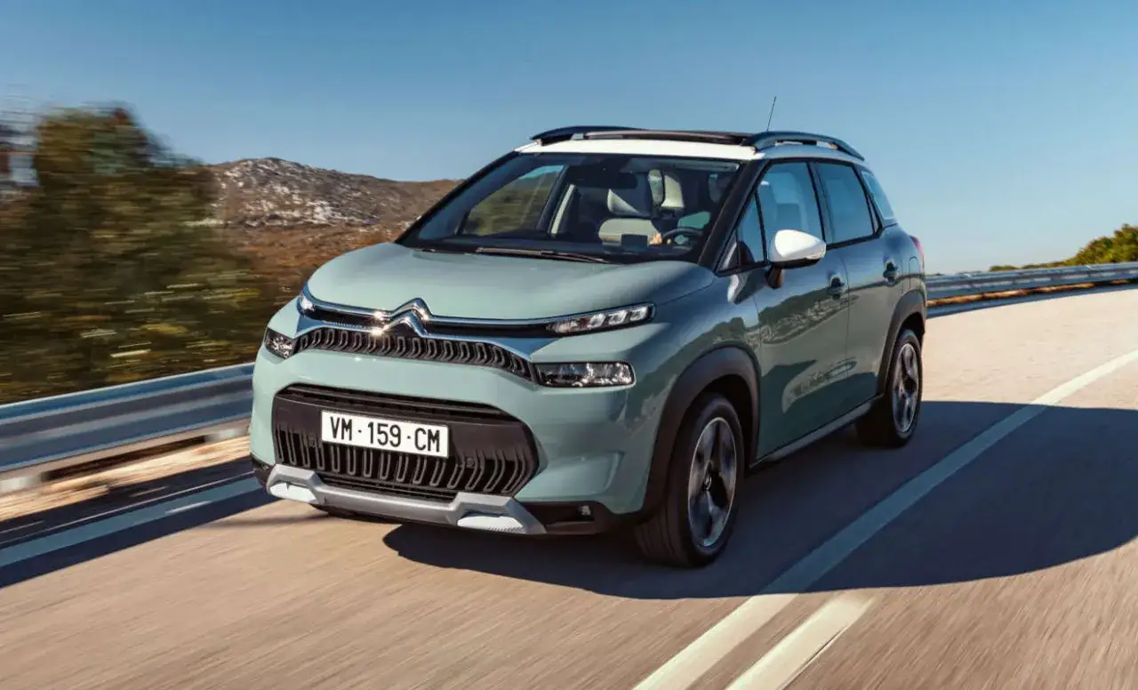 Ein mintgrüner Citroën C3 Aircross fährt auf einer sonnigen Straße. Trotz seines schicken Designs gibt es Berichte über Citroën C3 Aircross Probleme.