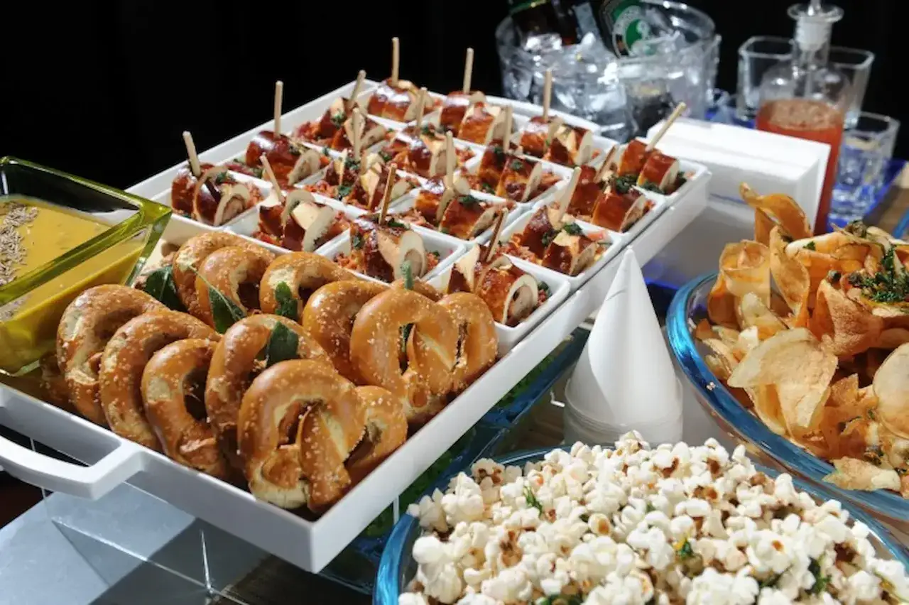 Stół pełen przekąsek: precle, popcorn, chipsy i mini roladeczki. Idealne finger food na imprezę.