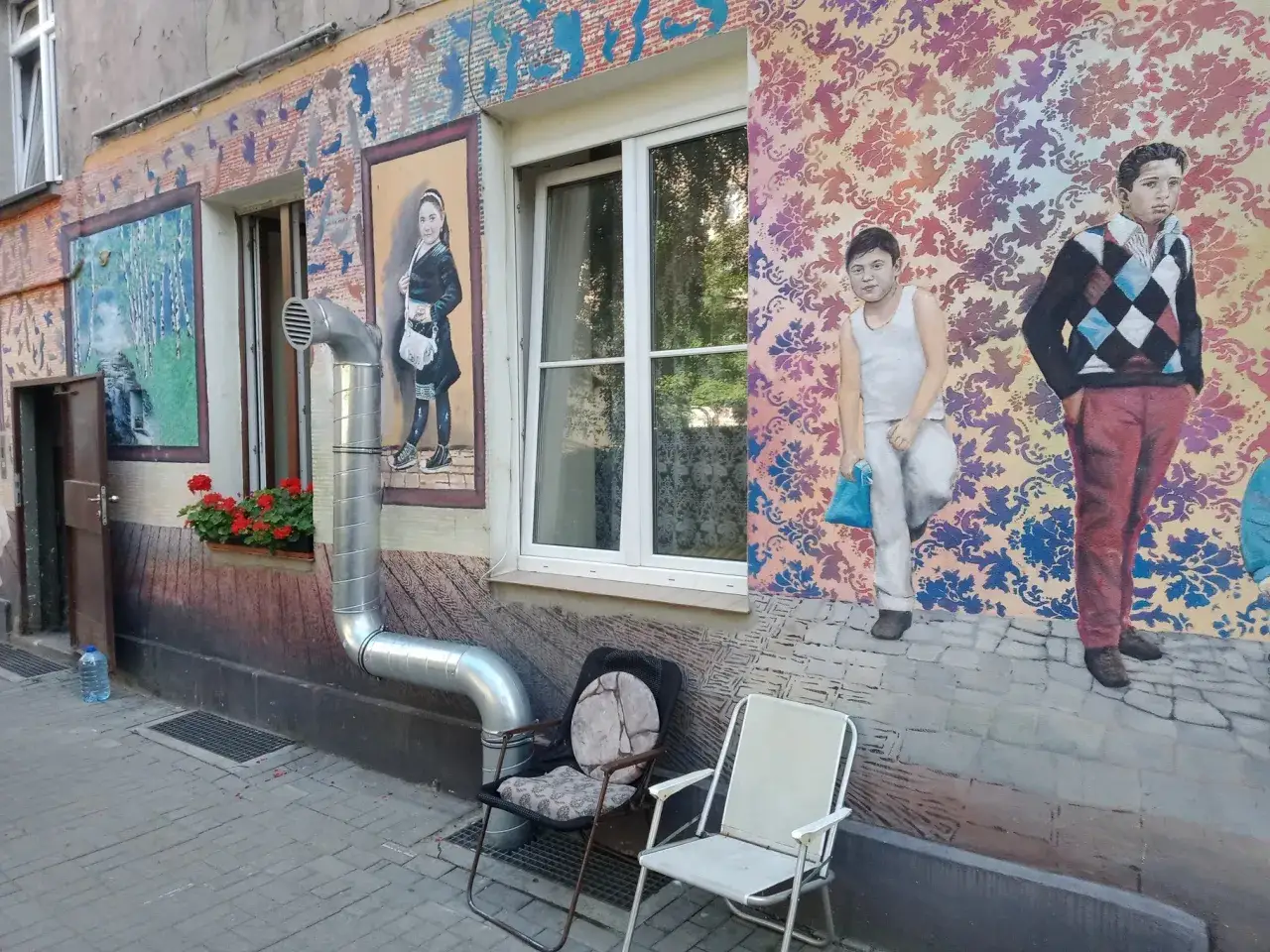 Kolorowe murale na **Nadodrzu** zdobią ścianę kamienicy. Dzieci na obrazach wyglądają jakby czekały na kogoś.