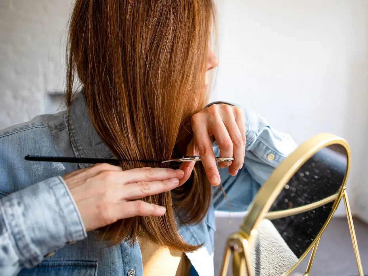 Frau schneidet sich mit Schere und Kamm die Haare, eine Anleitung f&uuml;r Stufenschnitt.