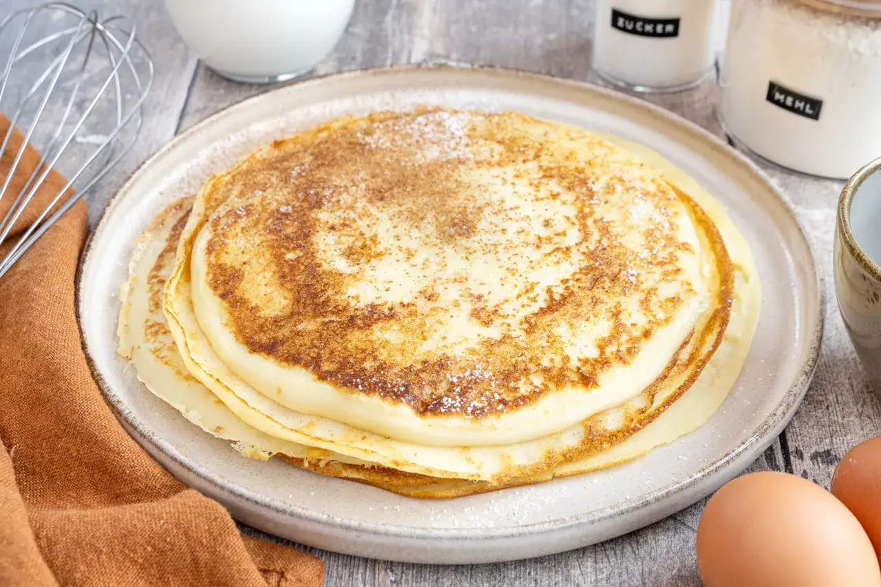 Ein Stapel goldbrauner Pfannkuchen, bestäubt mit Zimt und Zucker. Ein einfaches Pfannkuchen Rezept, das schnell gelingt.