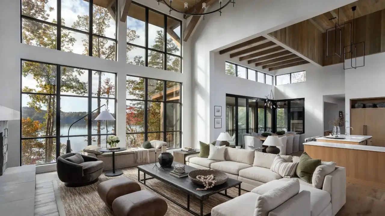 Großzügiges Wohnzimmer mit bodentiefen Fenstern, die auf einen See blicken. Die moderne Inneneinrichtung mit Holzakzenten schafft eine warme Atmosphäre.