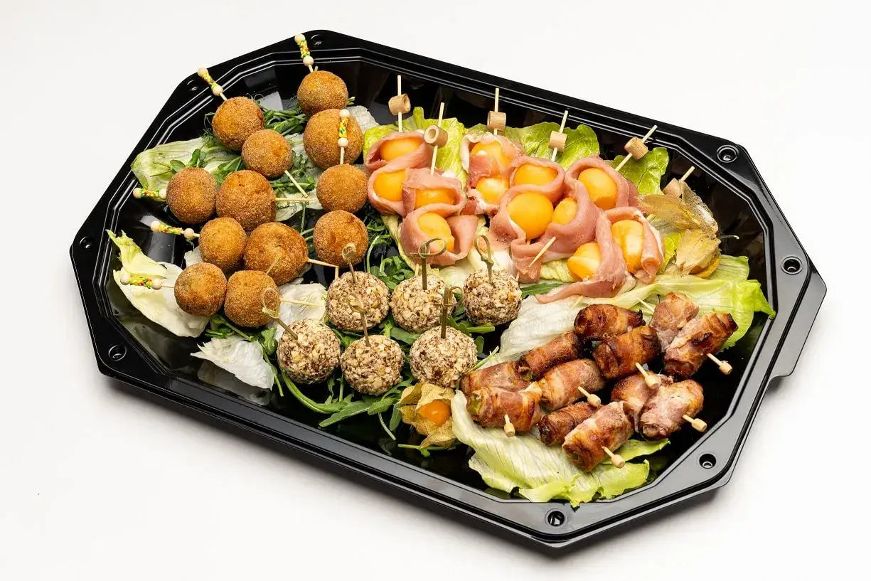 Taca z zimnymi przekąskami na wesele: kulki serowe w orzechach, melon w szynce, faszerowana papryka w boczku i kulki w panierce.