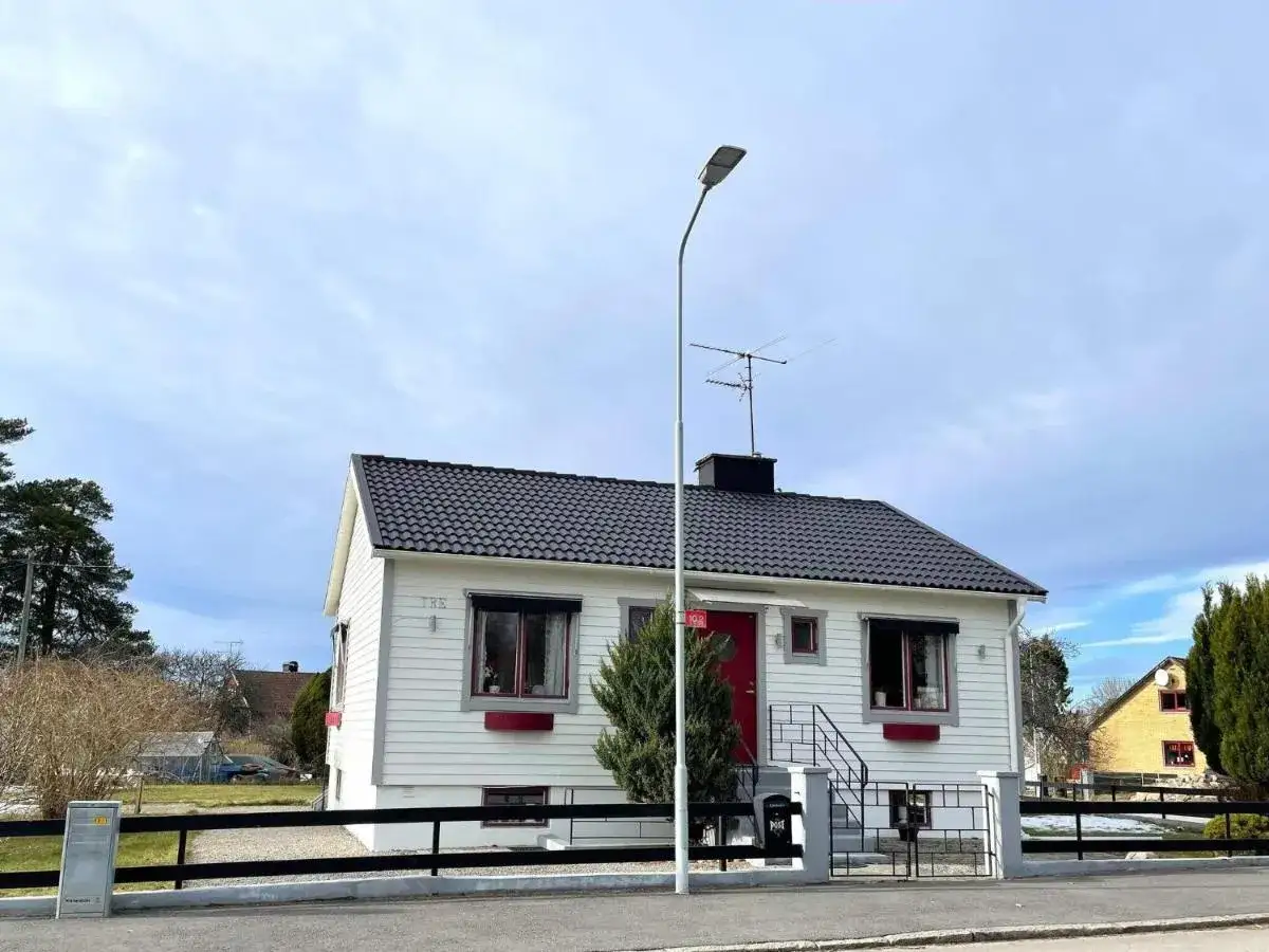 Vitt hus med röda detaljer, en fin entré och en liten trädgård. Ett mysigt vandrarhem i Mariestad.