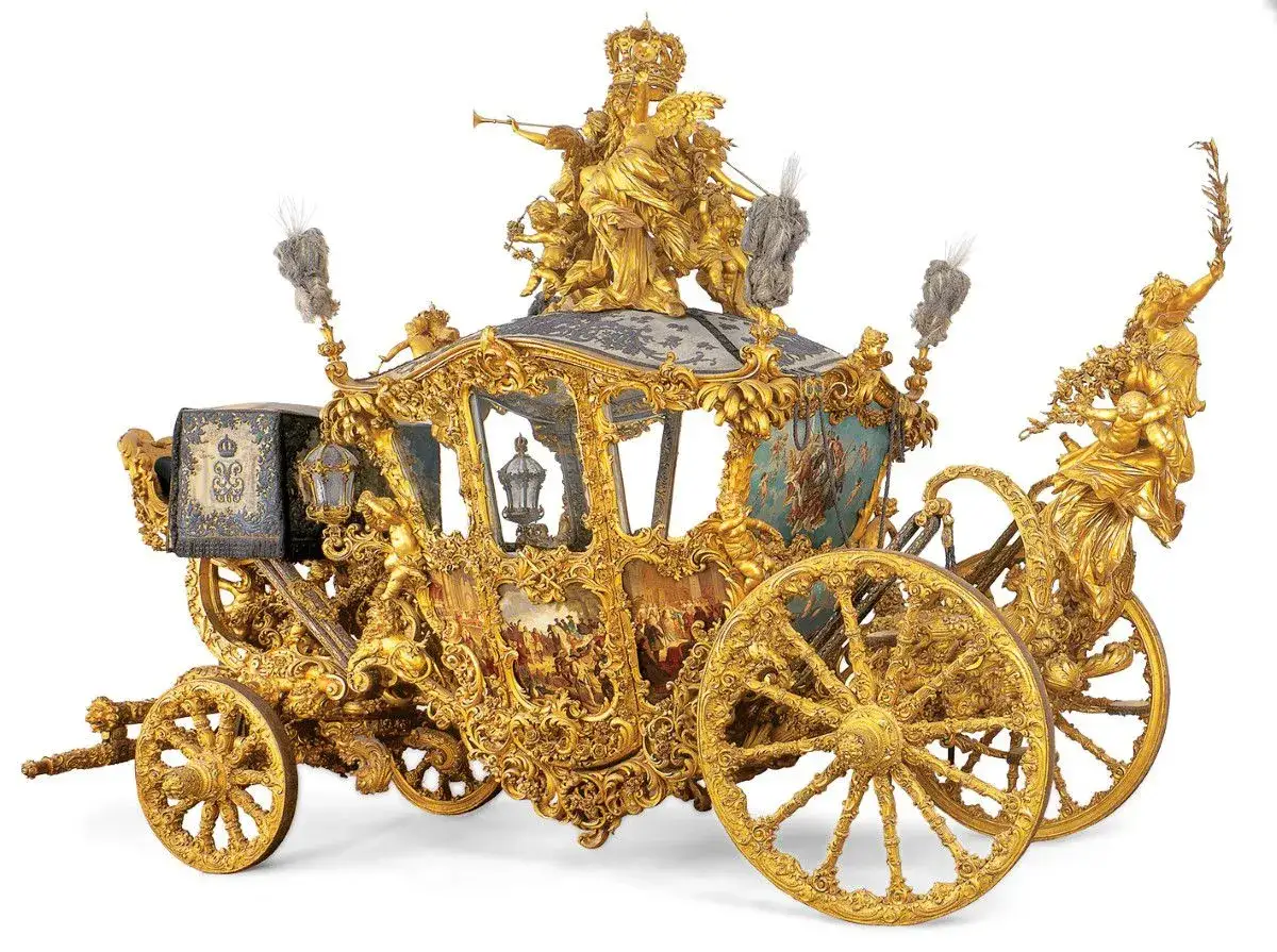 Goldener Prunkwagen im Marstall Museum, verziert mit Figuren und Malereien.