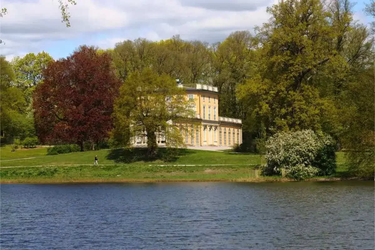 En vacker gul villa omgiven av grönska vid en sjö. En person tar en promenad i Stockholm.