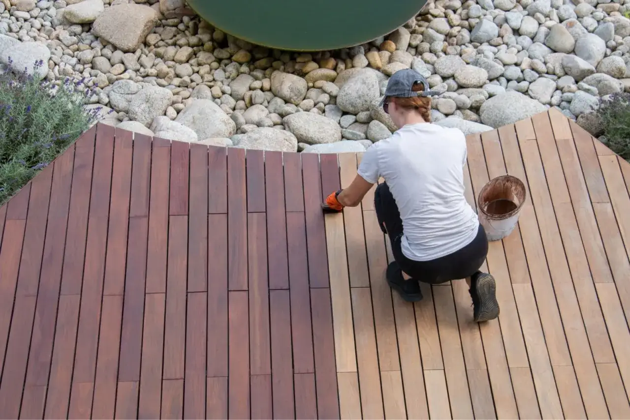 Application d'un lazur bois sur une terrasse en bois. La moitié est traitée, l'autre attend son tour.