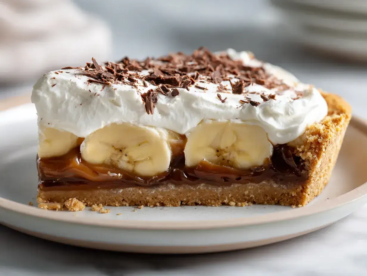 En bit kr&auml;mig banoffee paj med banan, kolas&aring;s, vispgr&auml;dde och chokladstr&ouml;ssel.