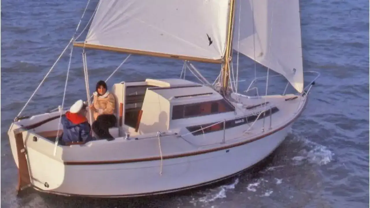 Un voilier Evasion 22 navigue sur une mer agitée, deux personnes à bord profitent de la brise.