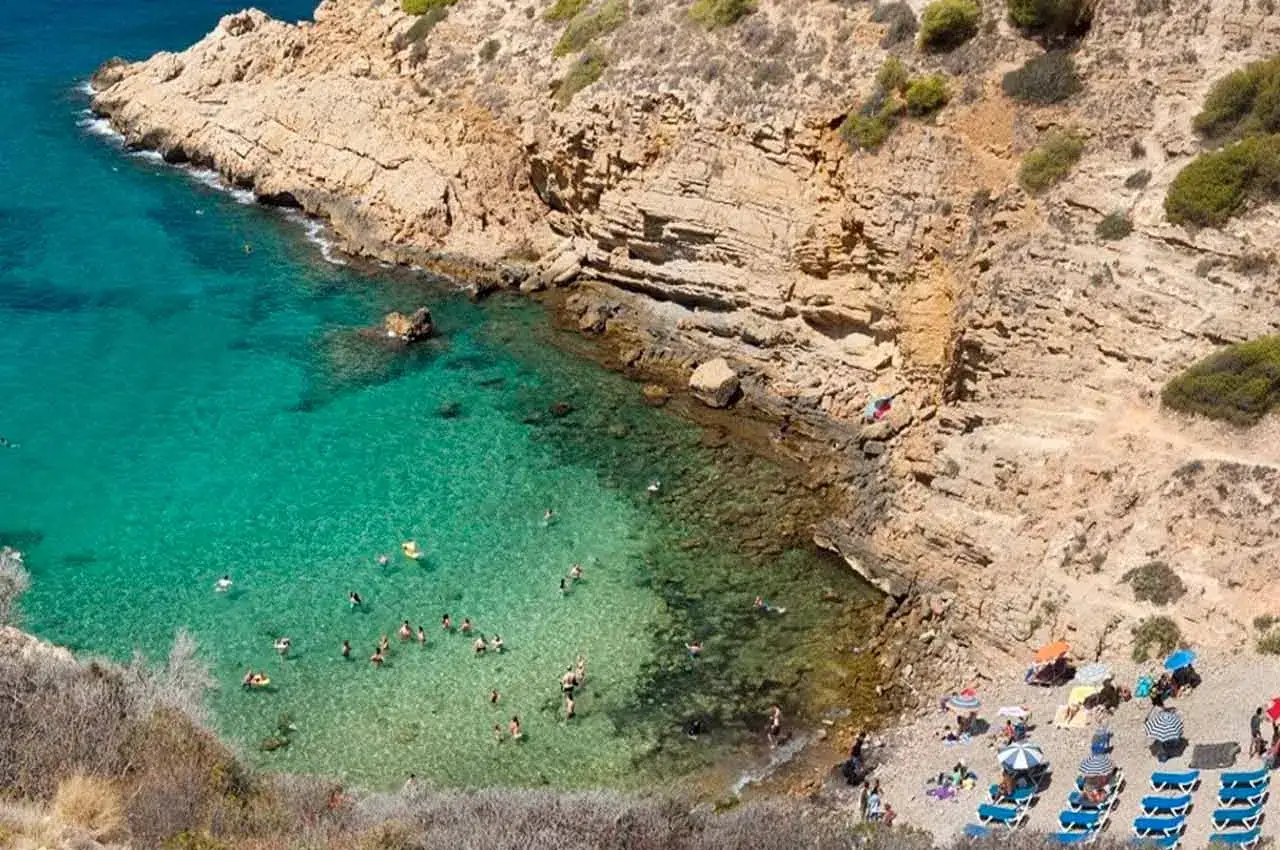 Cala escondida con aguas turquesas y gente disfrutando, un ejemplo de las playas bonitas cerca de Benidorm.