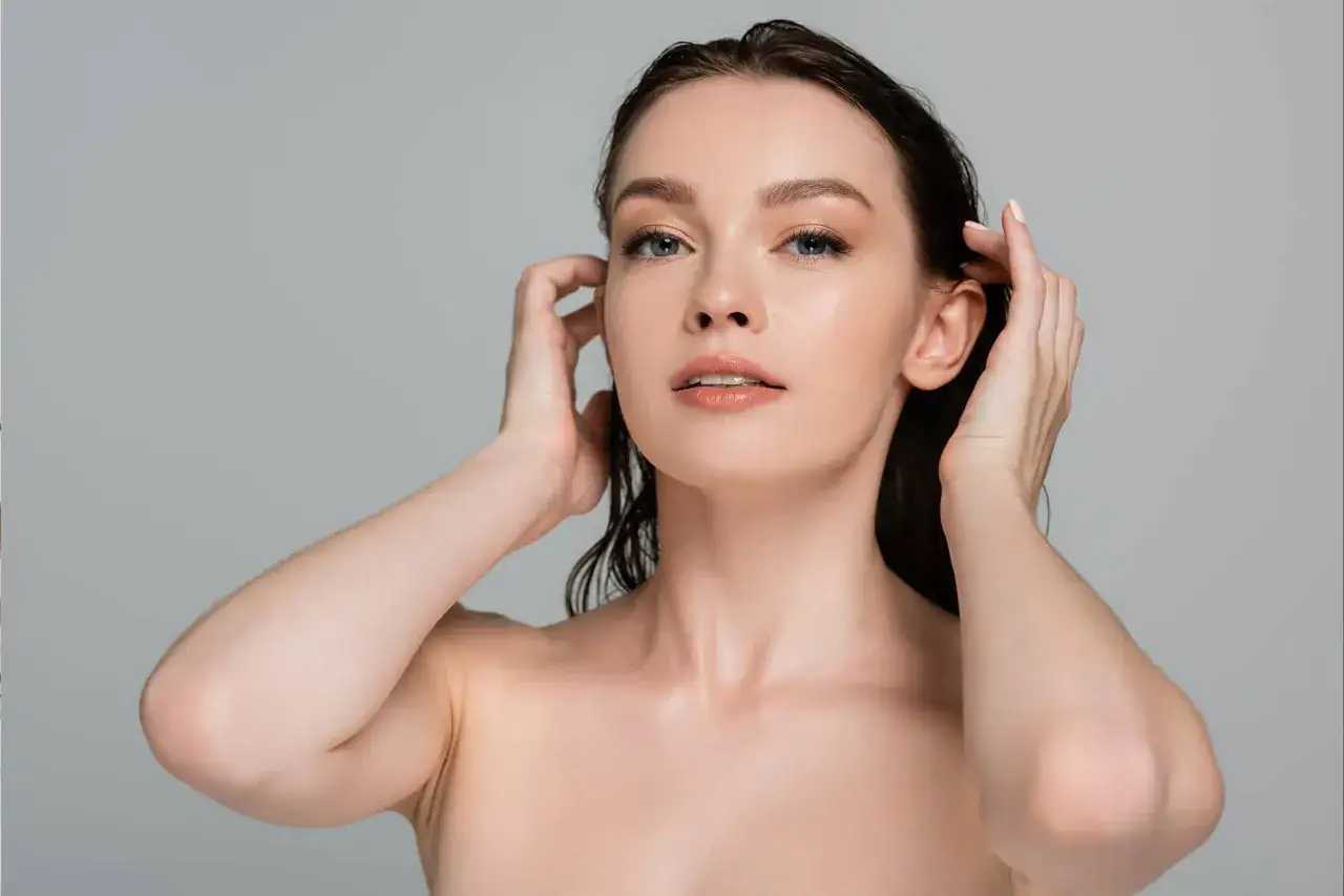 Kobieta z mokrymi włosami dotyka głowy, zastanawiając się, jaki peeling do skóry głowy wybrać dla zdrowych włosów.