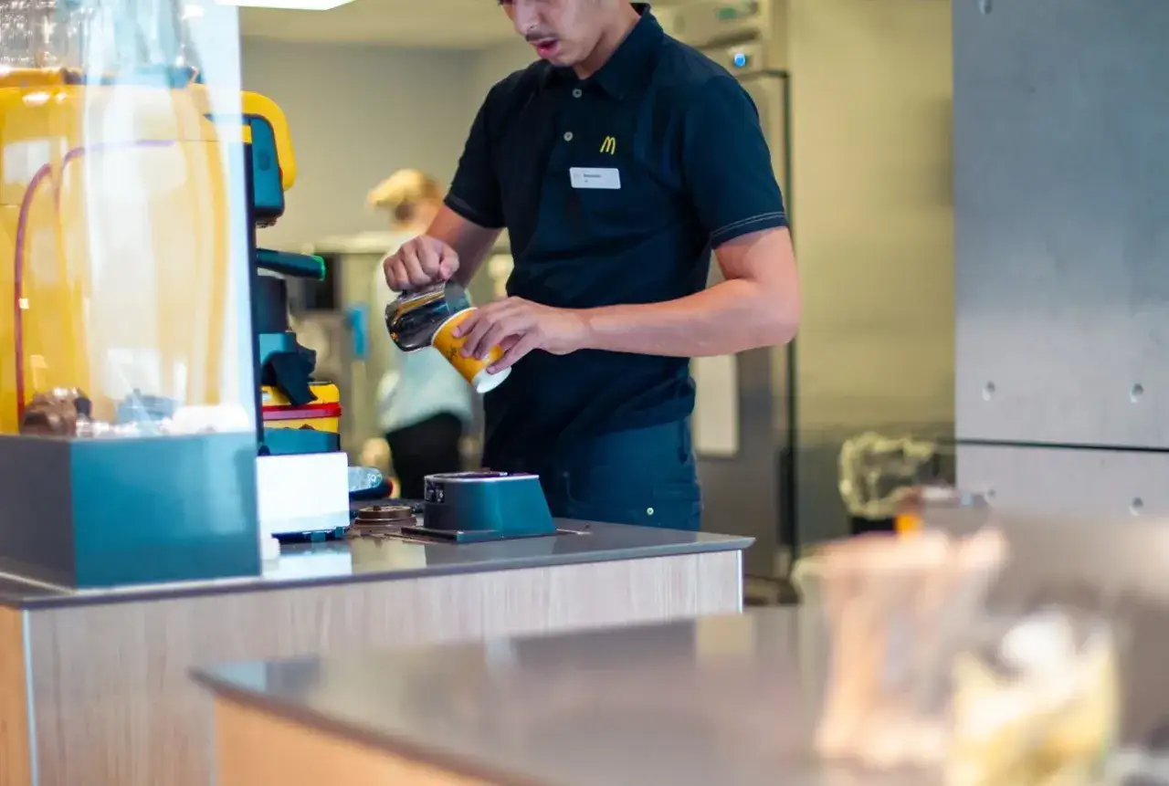 Pracownik McDonald's przygotowuje kawę. Ile zarabia pracownik McDonald's? To zależy od wielu czynników, ale praca ta daje stabilne zatrudnienie.