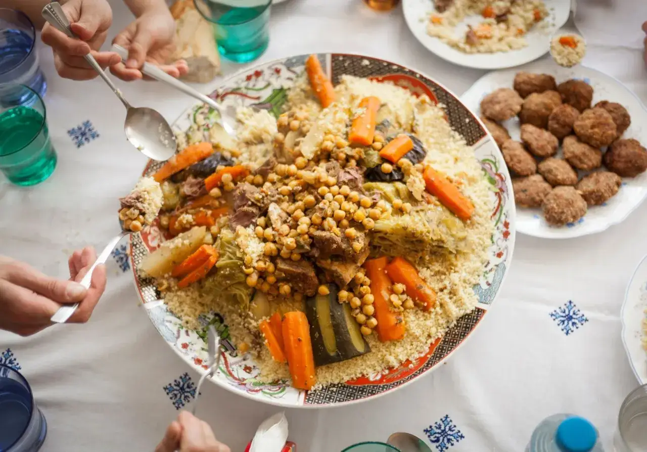 Un grand plat de couscous garni de légumes, de viande et de pois chiches, prêt à être dégusté. Une recette familiale qui réunit tout le monde.