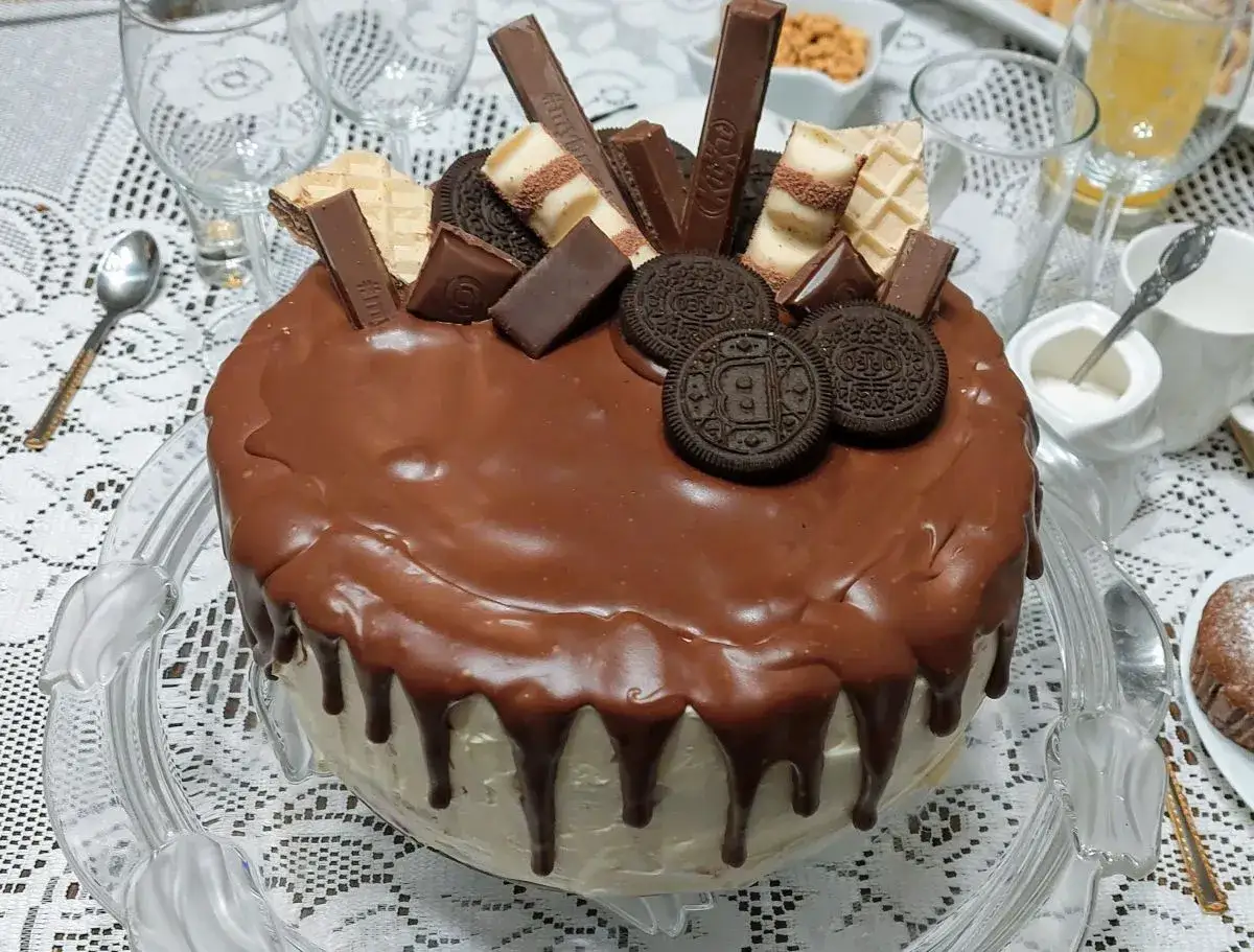Tort oblany polewą z prawdziwej czekolady, ozdobiony batonikami i ciasteczkami. Wygląda apetycznie!