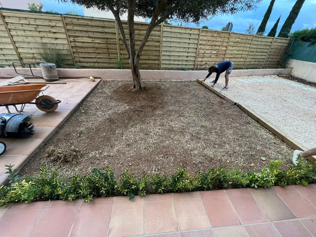 Hombre colocando madera para clavar c&eacute;sped artificial en un jard&iacute;n.