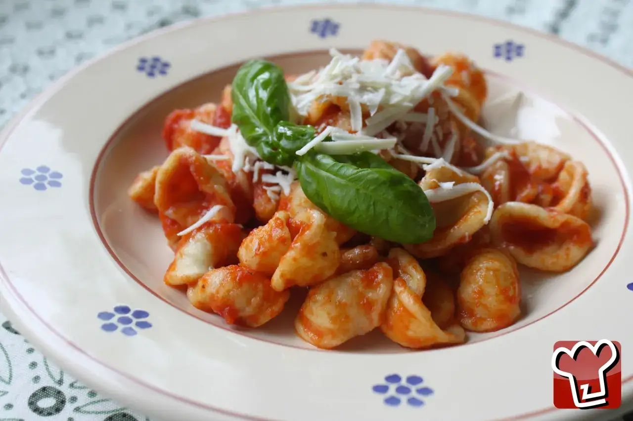 Orecchiette con sugo di pomodoro, ricotta e basilico, un classico piatto di pasta e ricotta alla pugliese.