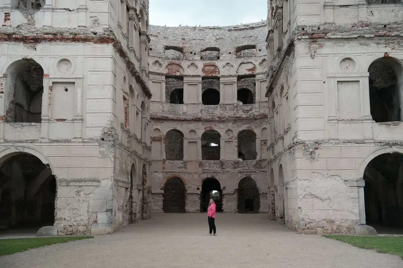 Ruiny zamku Krzyżtopór. Ciekawostki o tym miejscu kryją się w jego architekturze. Kobieta w różowej kurtce podziwia potęgę budowli.