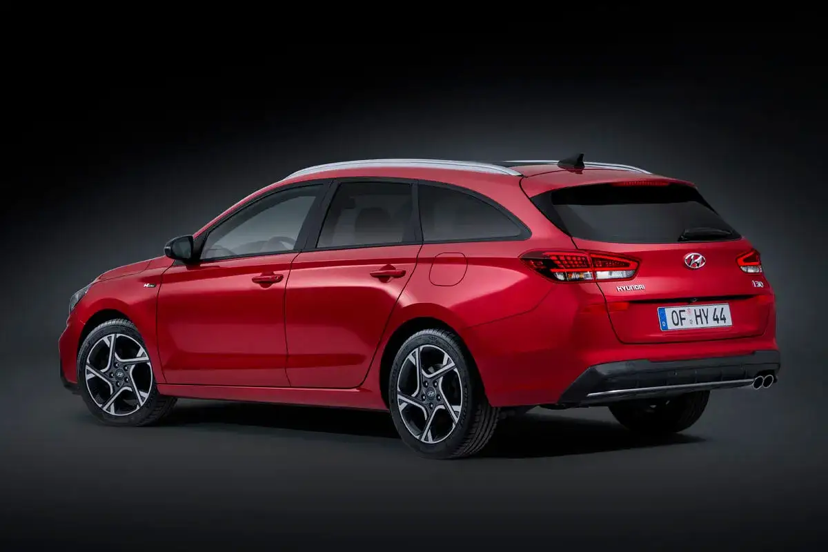 Czerwony Hyundai i30 hatchback zrelaksowany na ciemnym tle. Elegancka linia nadwozia i sportowe felgi podkreślają jego dynamiczny charakter.