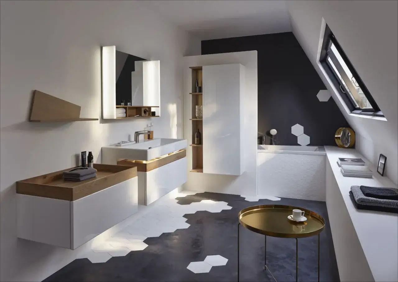 &Eacute;l&eacute;gante salle de bain sous comble, avec un lavabo moderne, une baignoire et des rangements blancs et bois. Le sol hexagonal et la fen&ecirc;tre de toit ajoutent du cachet.