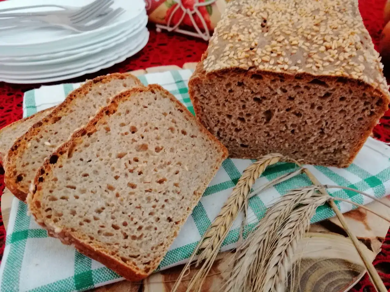 Chleb żytni razowy, posypany sezamem, z kilkoma kromkami obok. Idealny na zdrowe śniadanie.