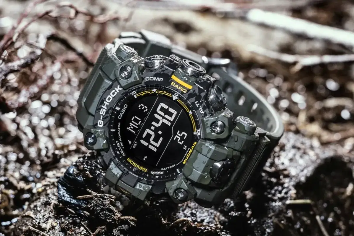 Zielony, odporny zegarek G-Shock Mudman leży na mokrej ziemi. Jego cyfrowy wyświetlacz pokazuje godzinę 12:40.