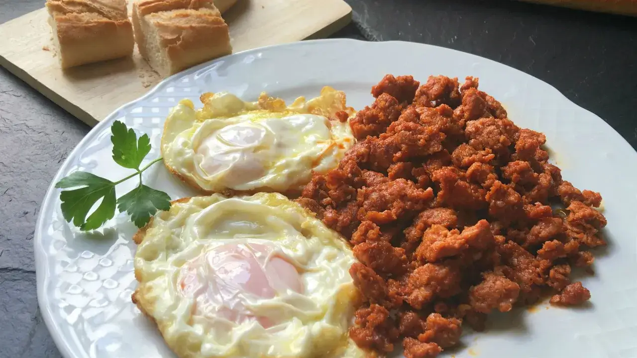 Dos huevos fritos con picadillo de chorizo, acompa&ntilde;ados de pan. Un plato perfecto para tus recetas con picadillo de chorizo.