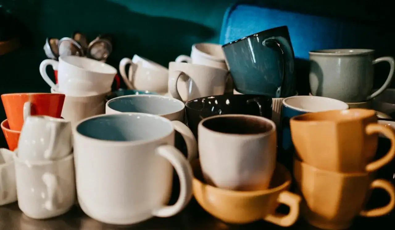Stos ceramicznych kubków w różnych kolorach. Idealne na poranną kawę lub herbatę, by zacząć dzień.