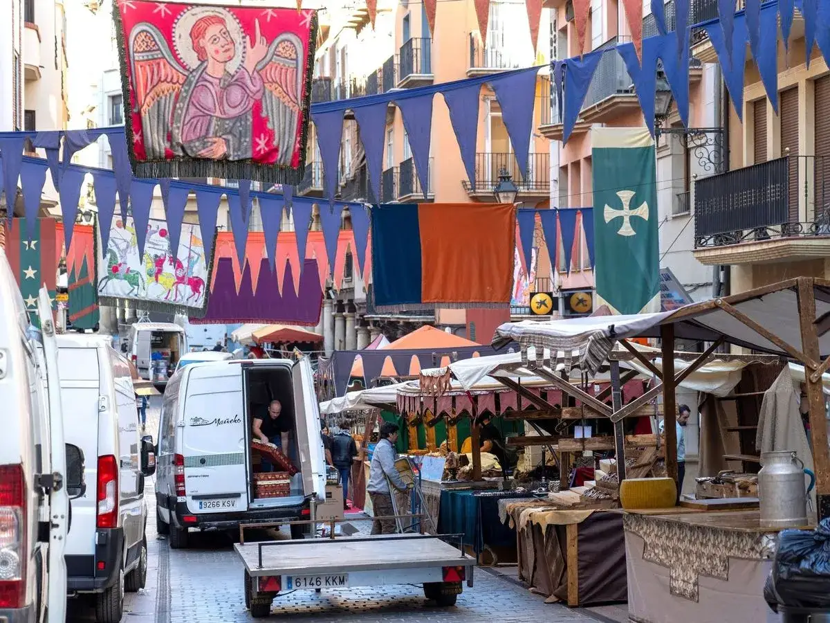 Mercado medieval con pendones y puestos. La partida de Diego se prepara para la fiesta.