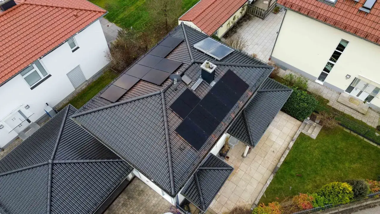 Dach mit Solarmodulen für die Anmeldung einer PV-Anlage. Ein Haus mit dunklen Dachziegeln und mehreren Reihen schwarzer Solarpaneele.